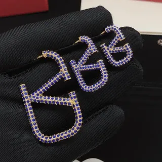 Brincos em tom dourado azul real com pavé em forma de letra