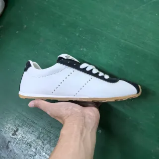 حذاء رياضي أبيض وأسود ثنائي اللون مثقوب