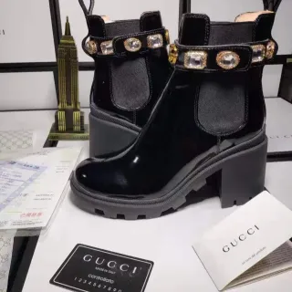 Gucci काले सोने की चमकदार पेटेंट लेदर क्रिस्टल-एम्बेलिश्ड स्ट्रैप एंकल बूट्स