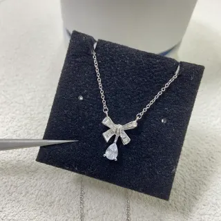 Collier avec pendentif en forme de nœud argenté blanc et pierres baguette sur les côtés